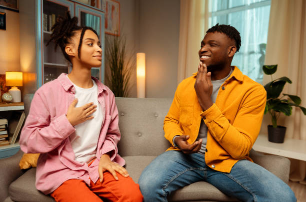 Smiling attractive African American couple wearing colorful clothes communicating with sign language