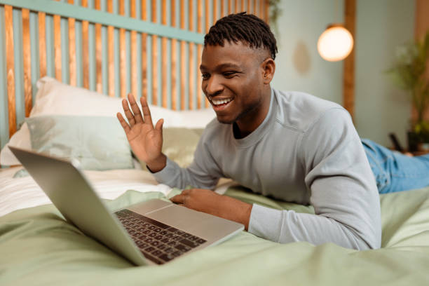 istock Handsome, smiling African American man lying on bed at home, using laptop, having video call 1926054202