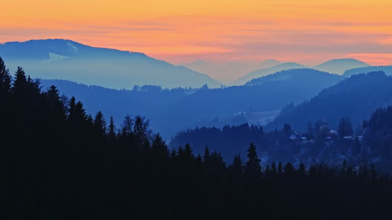 AERIAL Drone Shot of Majestic Silhouette Coniferous Trees and Foggy Mountains under Orange Sky during Golden Hour in Rogla, Slovenia