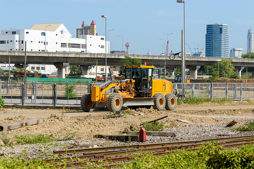 The large motor graders parked near the metal fence of the construction site after works, front view for the copy space.