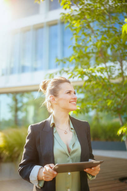 happy woman worker near office building using digital tablet