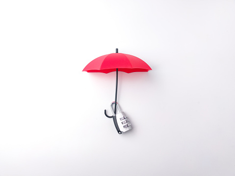 Silver padlock hanging on a red umbrella on a white background