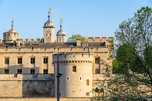 Woodstock, United Kingdom - June 29, 2015: Windsor Castle, Berkshire, England, United Kingdom. The original castle was built in the 11th century and is the longest-occupied palace in Europe. Castle entrance, tourists, green bushes, trees and vivid blue sky with clouds are in the image.