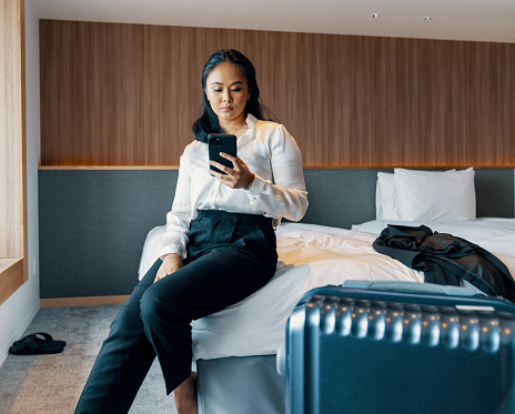 Young businesswoman looking at her smartphone  in a hotel room while on a business trip