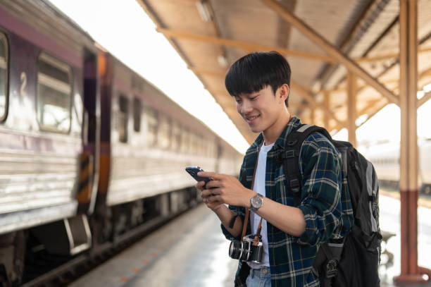 istock A happy Asian man tourist using his smartphone while standing at a platform in a railway station. 1926222296