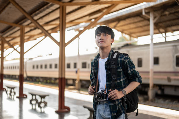 istock A handsome, happy young Asian man tourist backpacker standing at a platform in a railway station. 1926222297