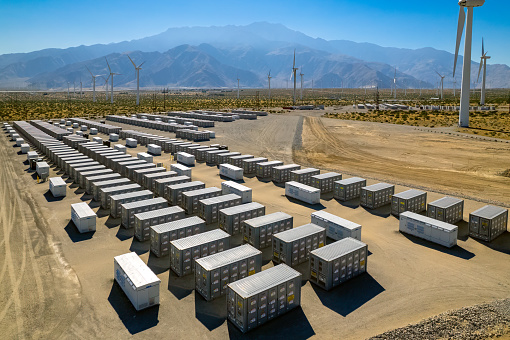 Aerial view of battery storage array at power plant in the desert near Palm Springs.  In the distance are wind turbines and San Jacinto mountain.
