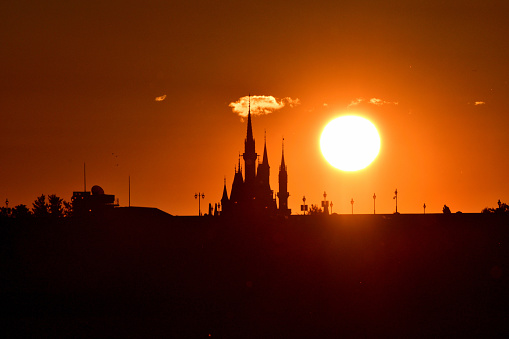 Tokyo, Japan-January 1, 2024: 
The first sunrise of the year 2024 over Cinderella Castle of Tokyo Disneyland, which was taken on the morning of January 1, 2024, from across a part of Tokyo Bay at Kasai Rinkai (Seaside) Park, Edogawa Ward, Tokyo, by telephoto lens.