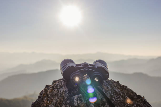 binoculars on top of rock mountain at beautiful sunset background.