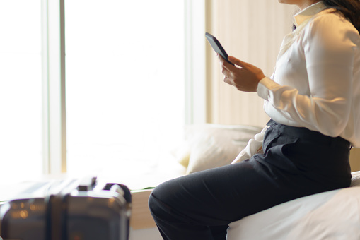 A woman who has just arrived at a hotel she is visiting on business puts down her travel bag and takes a break.