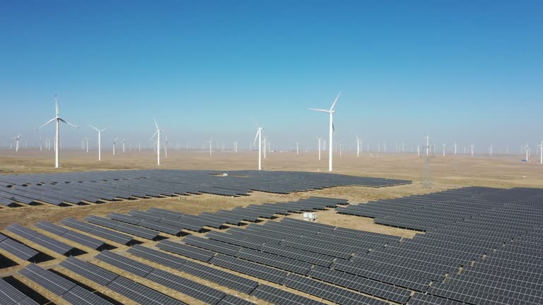 High-angle bird's-eye view of solar photovoltaic panels and wind turbines in the desert