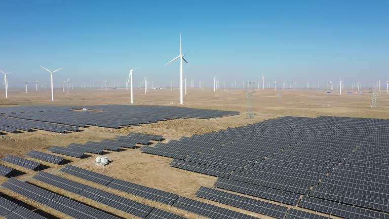 High-angle bird's-eye view of solar photovoltaic panels and wind turbines in the desert