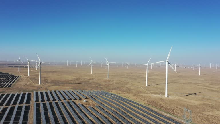 High-angle bird's-eye view of solar photovoltaic panels and wind turbines in the desert