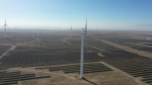 High-angle bird's-eye view of solar photovoltaic panels and wind turbines in the desert