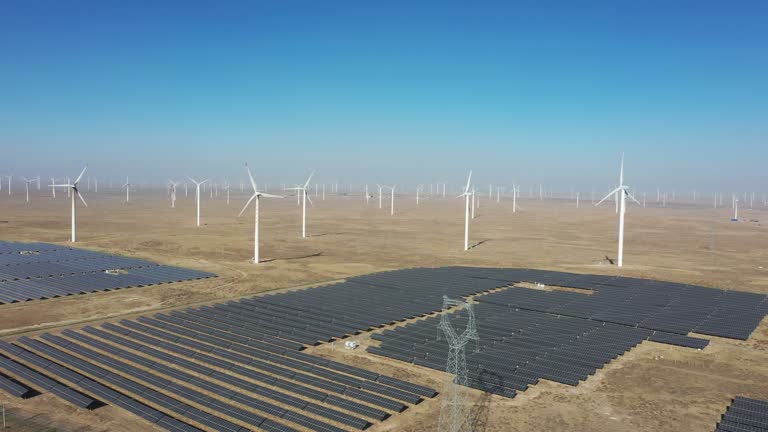 High-angle bird's-eye view of solar photovoltaic panels and wind turbines in the desert