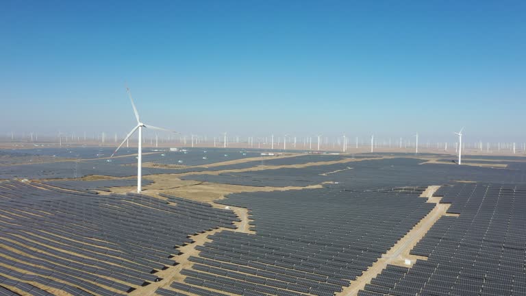 High-angle bird's-eye view of solar photovoltaic panels and wind turbines in the desert