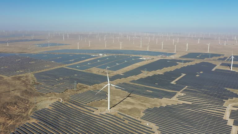 High-angle bird's-eye view of solar photovoltaic panels and wind turbines in the desert