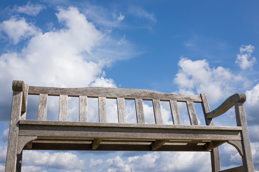 Taking a picture of an old wooden bench chair against the blue sky