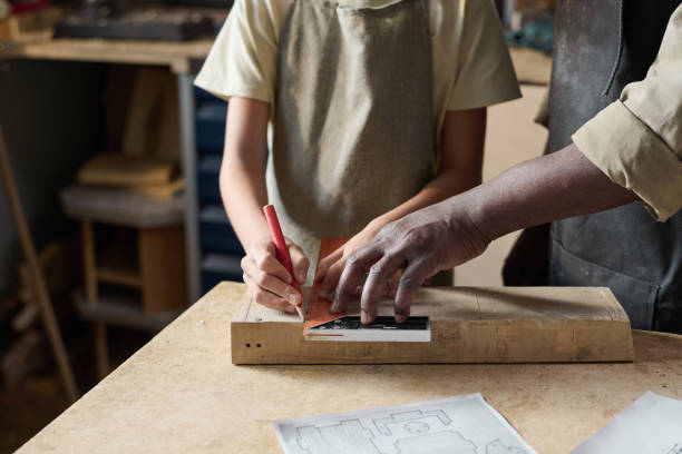 istock Child Measuring Wooden Board in Workshop with Teacher 1926654962