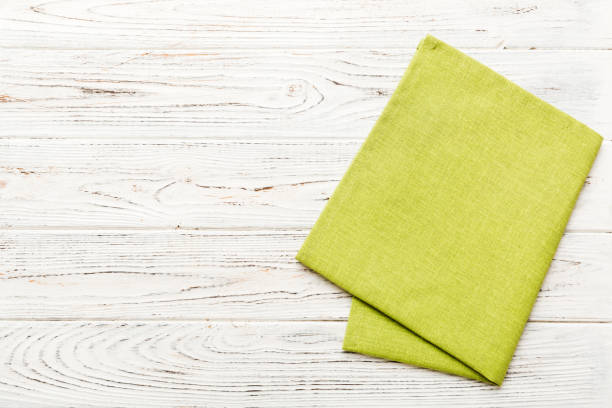 istock top view with green kitchen napkin isolated on table background. Folded cloth for mockup with copy space, Flat lay. Minimal style 1926660254