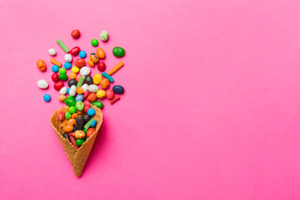 istock waffle cone full of assorted traditional candies falling out on colored background with copy space. Happy Holidays sale concept 1926660268