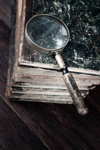 Vintage magnifying glass with books on table