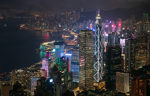 Panoramic view of Hong Kong City during day to night. View of financial district high-rise and residential buildings lighting up after sunset from mountain peak Observation