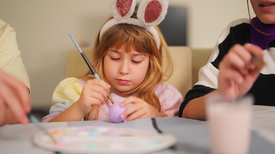 A young family is painting Easter eggs in the living room at home.