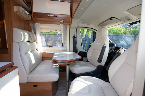 campervan modern wooden table and white seat interior in luxury motor home on rv vanlife concept