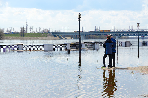 Gomel, Belarus - April 9, 2023: April flood in city limits. Unidentified people are on flooded embankment of Sozh River, Gomel, Belarus