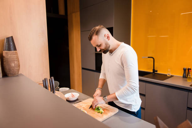 istock Bearded man cutting vegetables for salad on kitchen 1926737303