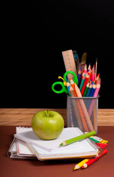 istock Magnifying glass, scissors, colored paper, textbooksboard, books, pencils, opened empty notebook against a dark background 1926740942