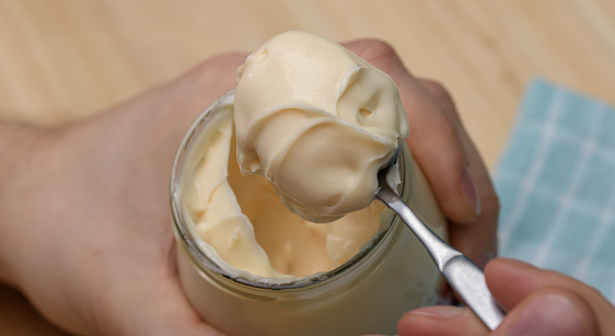 Spoon full of creamy mayonnaise close-up, mayonnaise sauce isolated