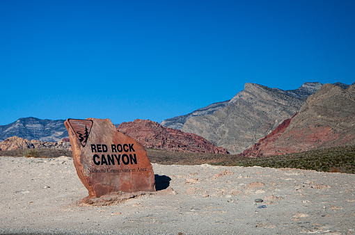 Red Rock Canyon stone sign at entrance to park with mountains behind
