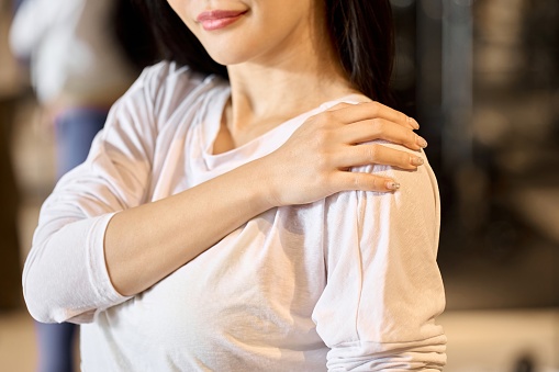 Woman hurting her shoulder at the gym