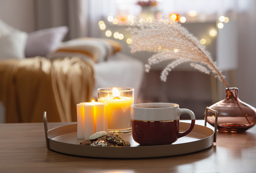 cup of tea with burning candles in cozy home