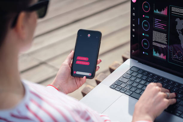 istock A woman uses chatbot on smartphone while working with a laptop outdoors 1926797033