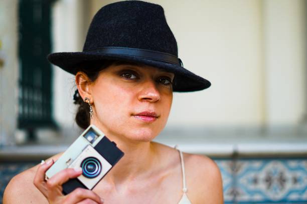 Girl wearing an elegant hat posing with an analog camera
