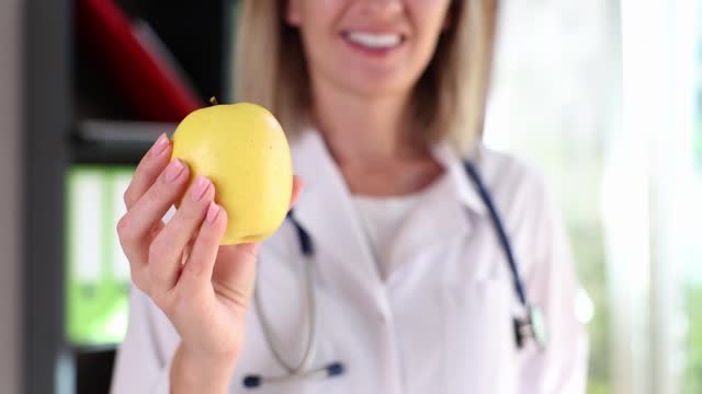 Doctor holds yellow apple and recommends healthy lifestyle