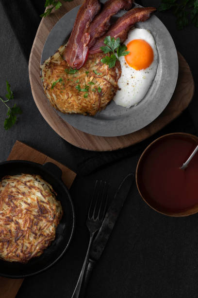 Homemade Hash browns with fried bacon and  egg on a dark background