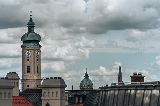 A clock tower against buildings on a cloudy day in Munich, Germany