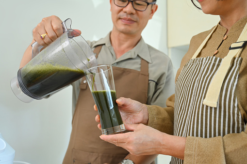 Middle age couple preparing healthy smoothie in kitchen. Healthy lifestyle and dieting concept.