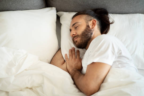 istock Top view of sleeping bearded young man lying in bed 1926849594