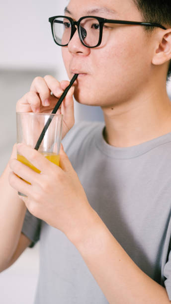 istock Close Up Asian Man Drink Orange Juice Using Straw. 1926851702