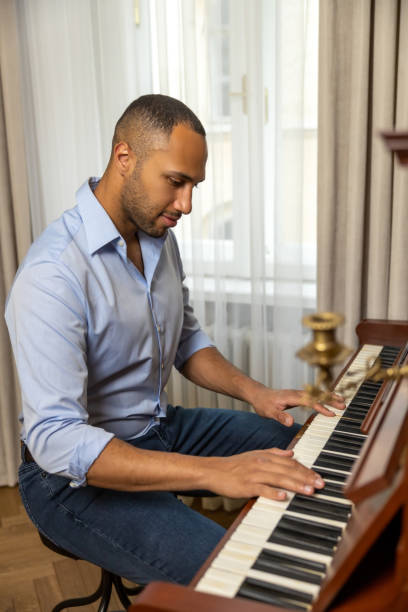 istock Man sitting at piano  and playing at home 1926860176