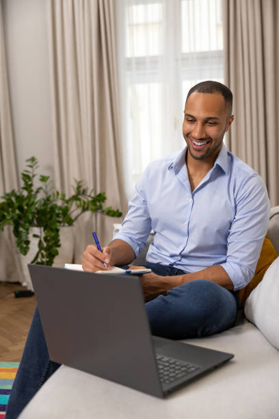 istock Man freelancer working online on laptop while sitting on couch at home 1926860698