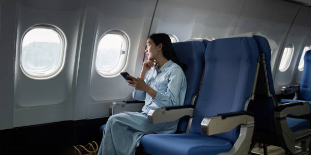 istock Asian people female person onboard, airplane window, using mobile while on the plane 1926880517