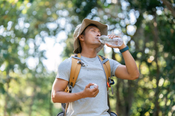 istock Young man backpacker traveling alone in forest. Attractive male traveler drinking water while walking in nature wood during holiday vacation trip 1926883747