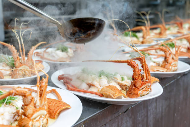 The chef's hand is operating the cooked lobster on the plate