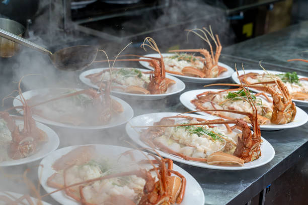 The chef's hand is operating the cooked lobster on the plate